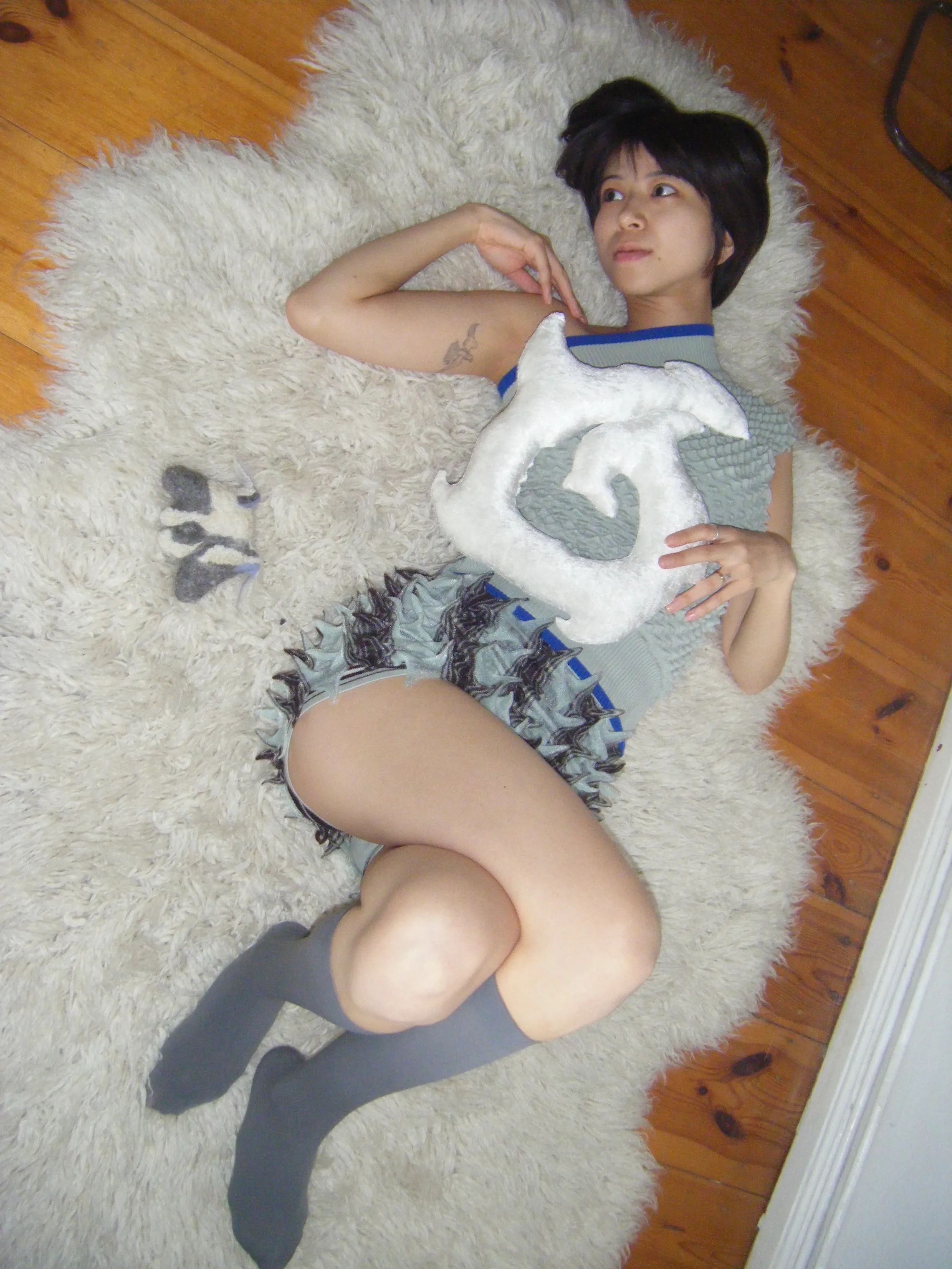 Person holding soft sculptural creature with mint green tentacles against neutral background